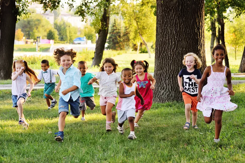Group of children running toward the camera on a green lawn
